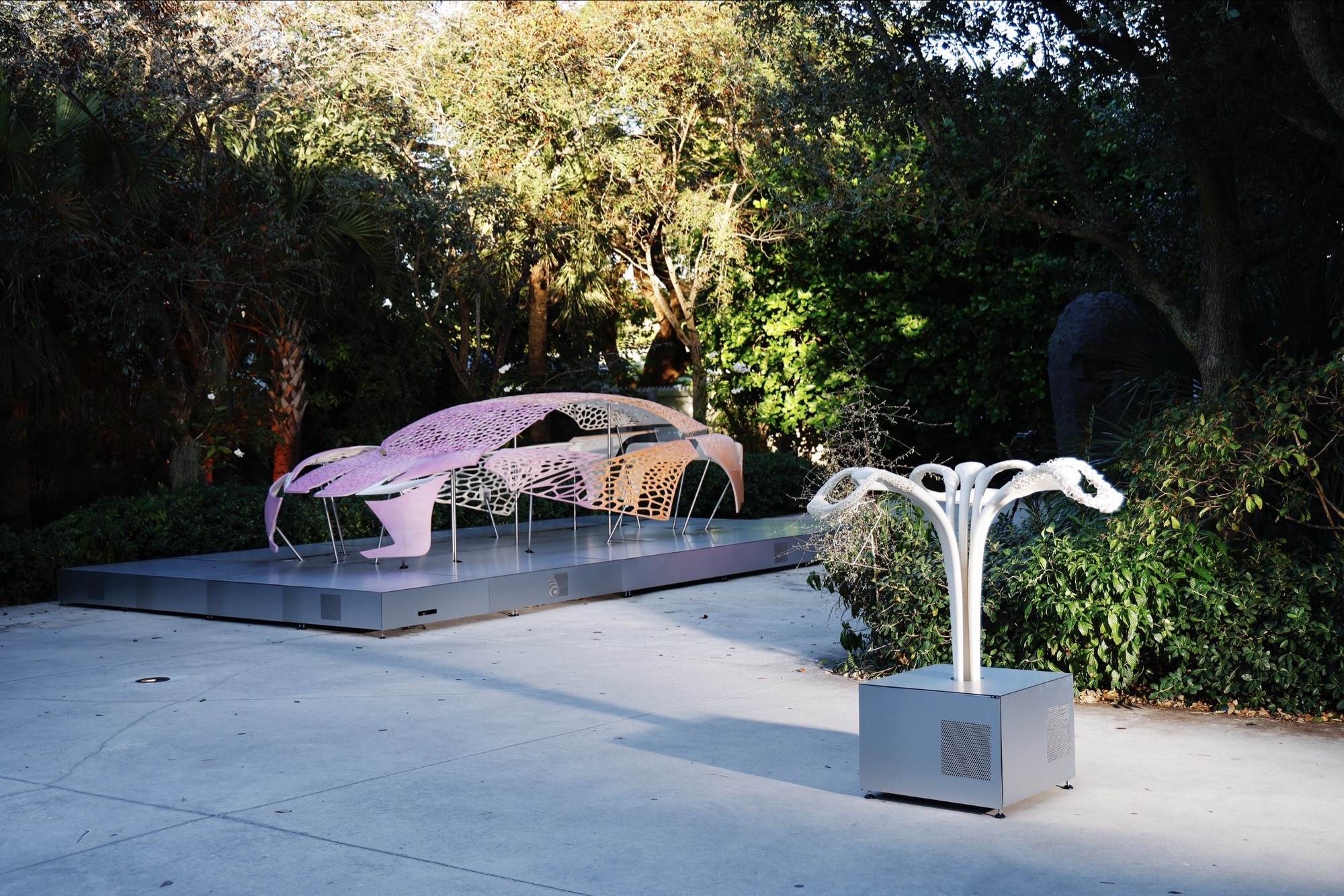 View of outside exhibition setup, the three floral object standing front right, the car model further in the background.