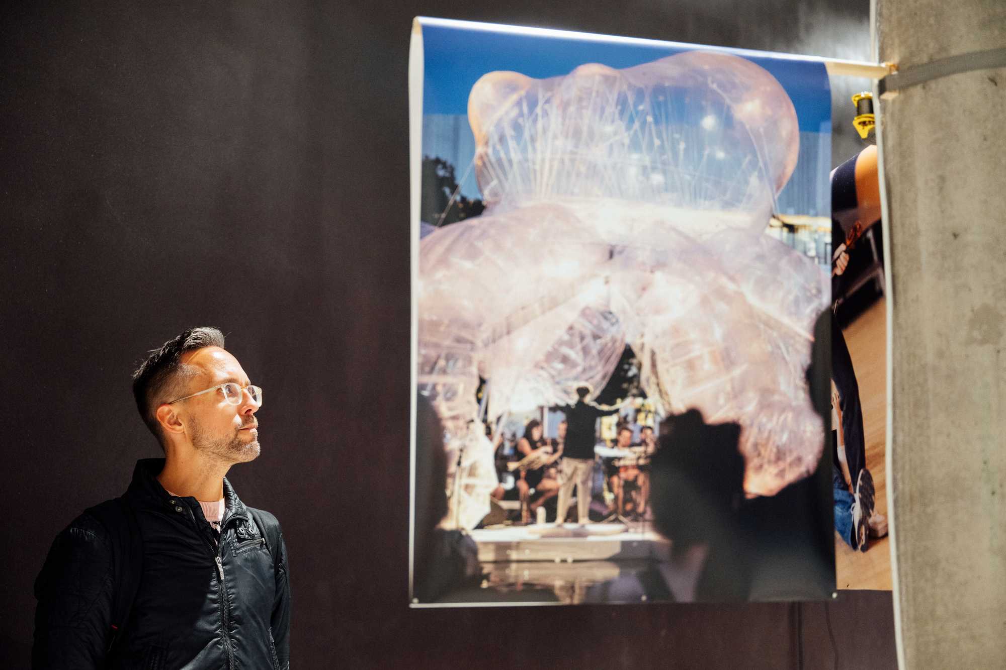 Ein·e einzelne·r Besucher·in betrachtet nachdenklich die Ausstellungsmaterialien im geschwungenen Gang