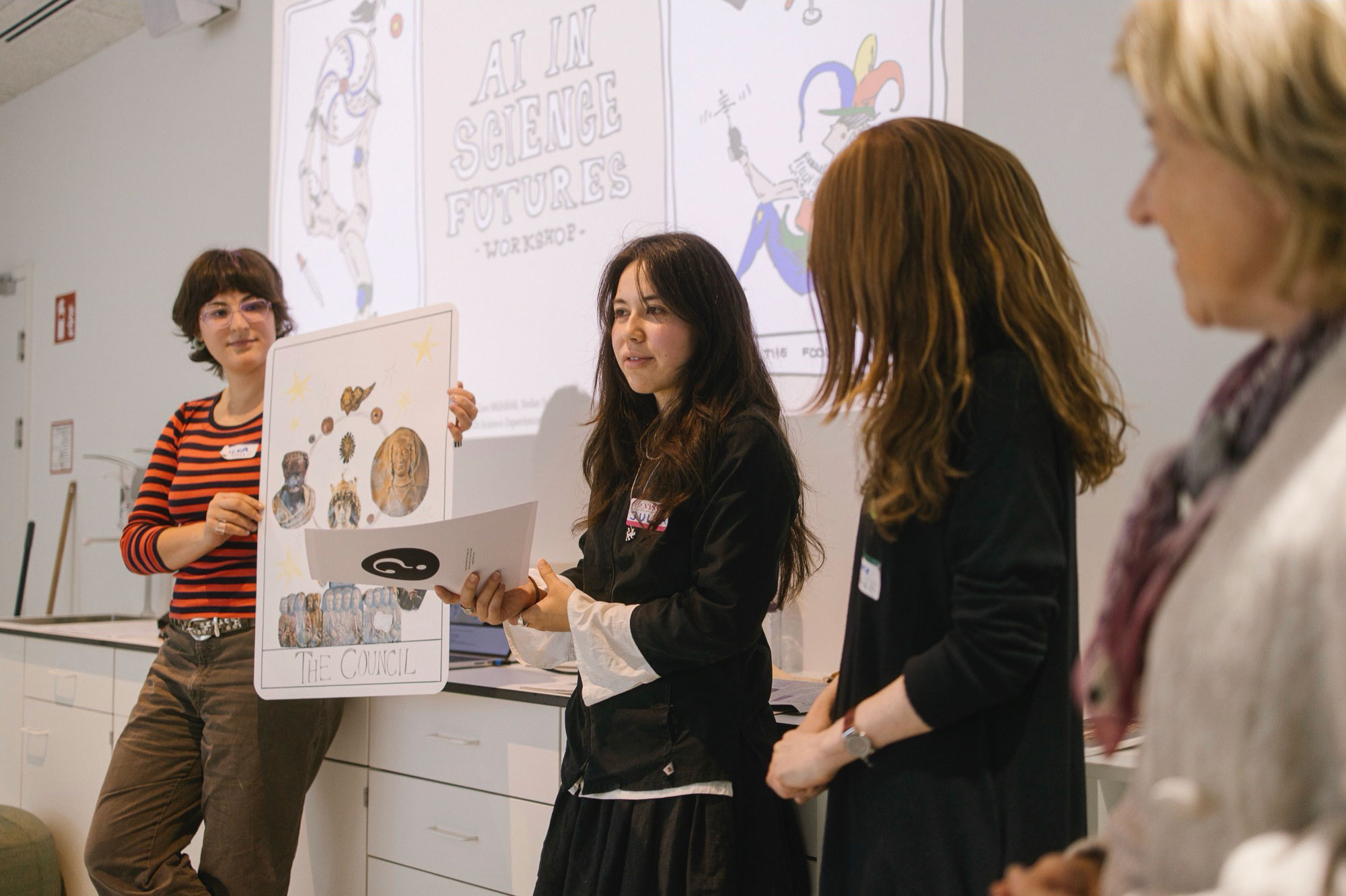 A group of people presenting their poster, holding sheets of paper in front of a projection of the workshop title.